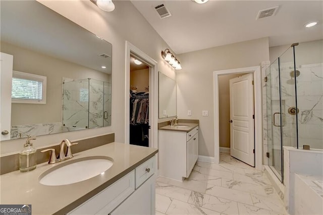full bath featuring marble look tile flooring, a marble finish shower, two vanities, recessed lighting, and a spacious closet