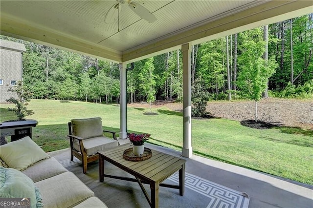 view of patio featuring a ceiling fan, an outdoor living space, and a wooded view
