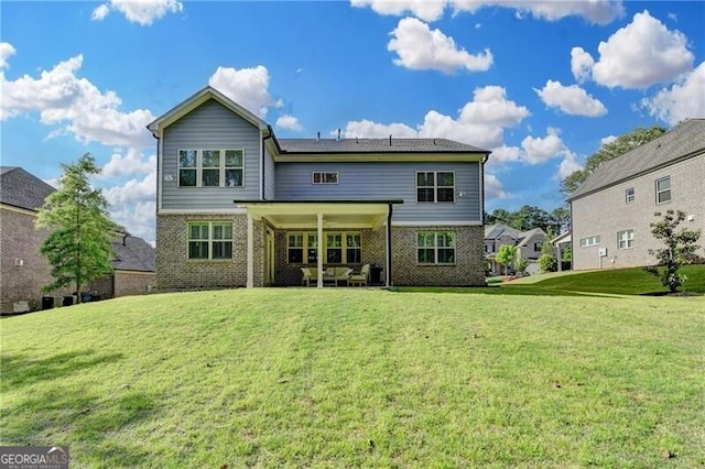 rear view of property featuring brick siding, a yard, and a patio