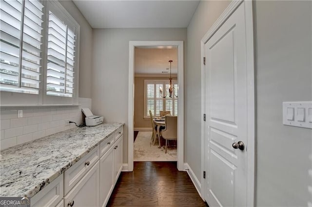 bathroom with wood finished floors, baseboards, a chandelier, and decorative backsplash