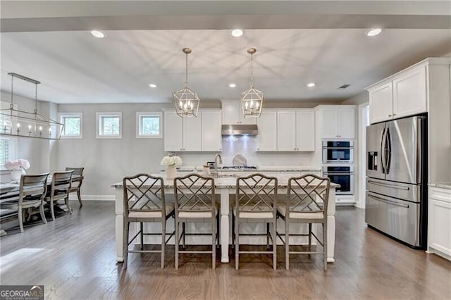 kitchen with appliances with stainless steel finishes, under cabinet range hood, a chandelier, a breakfast bar area, and recessed lighting