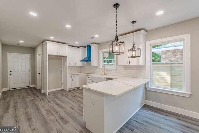 3275 Dodson Dr, East Point, GA 30344 - kitchen with wall chimney range hood, a peninsula, white cabinets, light stone countertops, and recessed lighting