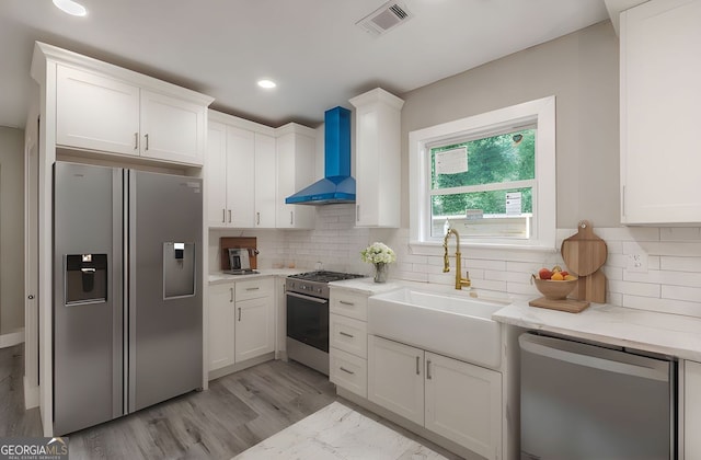 3275 Dodson Dr, East Point, GA 30344 - kitchen with appliances with stainless steel finishes, wall chimney exhaust hood, white cabinetry, a sink, and tasteful backsplash