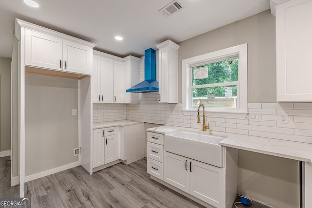 3275 Dodson Dr, East Point, GA 30344 - kitchen featuring wall chimney exhaust hood, a sink, light stone counters, light wood finished floors, and backsplash