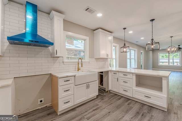3275 Dodson Dr, East Point, GA 30344 - kitchen featuring wall chimney range hood, a sink, light wood finished floors, a peninsula, and decorative backsplash