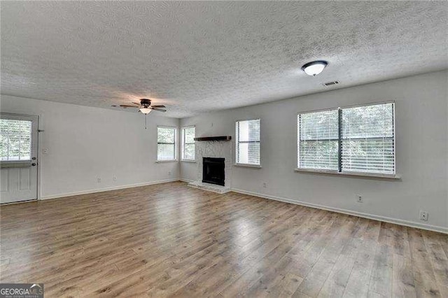 4278 Trotters Ln, Auburn, GA 30011 - unfurnished living room featuring wood finished floors, a textured ceiling, a ceiling fan, and a fireplace with raised hearth