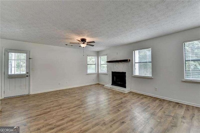 4278 Trotters Ln, Auburn, GA 30011 - unfurnished living room featuring wood finished floors, a textured ceiling, ceiling fan, and a fireplace with raised hearth