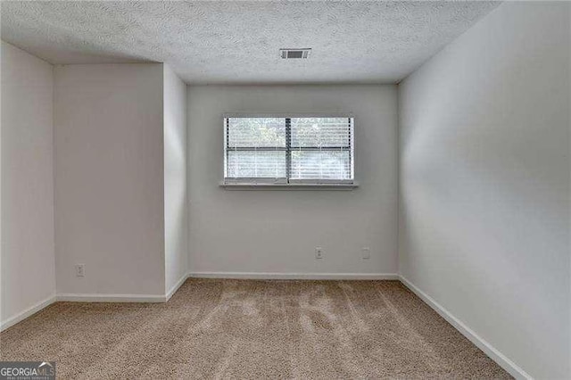 carpeted spare room featuring a textured ceiling and baseboards