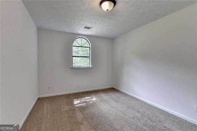 spare room with carpet flooring, a textured ceiling, and baseboards