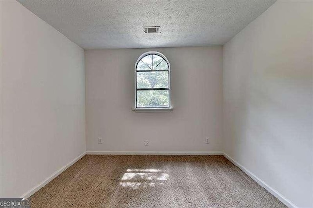carpeted empty room with a textured ceiling and baseboards