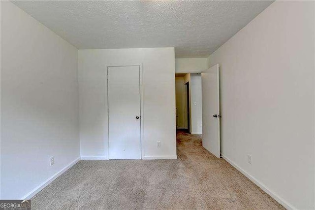 unfurnished bedroom with carpet, a textured ceiling, and baseboards