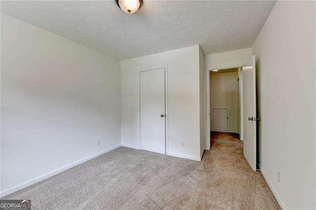 unfurnished bedroom with carpet, a textured ceiling, and baseboards