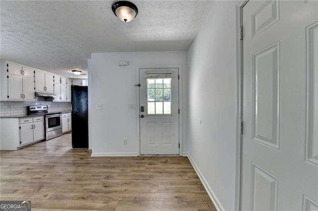 4278 Trotters Ln, Auburn, GA 30011 - kitchen with stainless steel stove, freestanding refrigerator, a textured ceiling, light wood-type flooring, and white cabinets