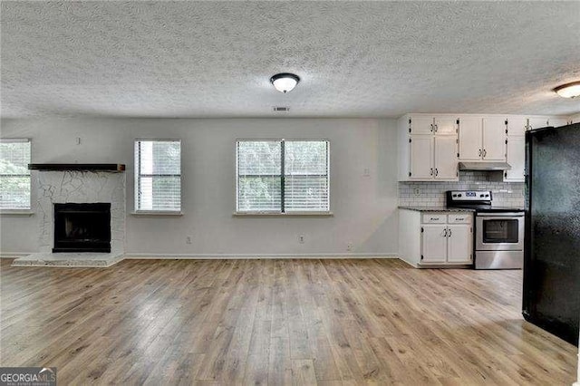 4278 Trotters Ln, Auburn, GA 30011 - kitchen with stainless steel range with electric cooktop, under cabinet range hood, light wood-type flooring, white cabinets, and a textured ceiling