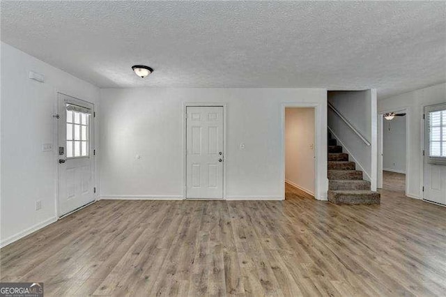 4278 Trotters Ln, Auburn, GA 30011 - unfurnished living room featuring stairs, a textured ceiling, and wood finished floors