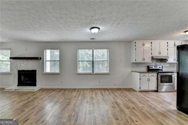 4278 Trotters Ln, Auburn, GA 30011 - kitchen featuring stainless steel electric range oven, under cabinet range hood, white cabinetry, light wood-style floors, and freestanding refrigerator