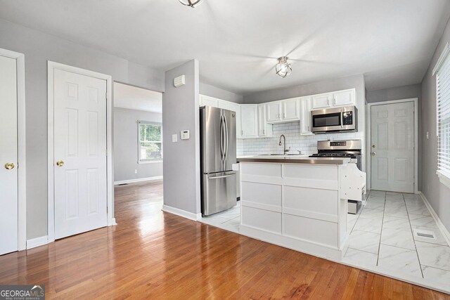 3650 Croft Pl NW, Atlanta, GA 30331 - kitchen with appliances with stainless steel finishes, a sink, white cabinetry, baseboards, and an island with sink