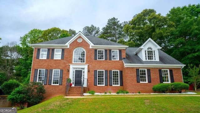colonial home featuring a front yard and brick siding