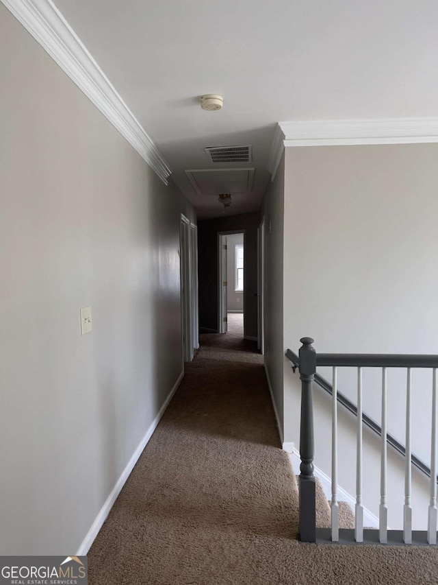 hall featuring crown molding, carpet flooring, baseboards, and attic access