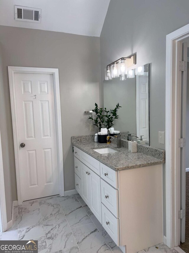 bathroom with vanity, marble finish floors, and baseboards