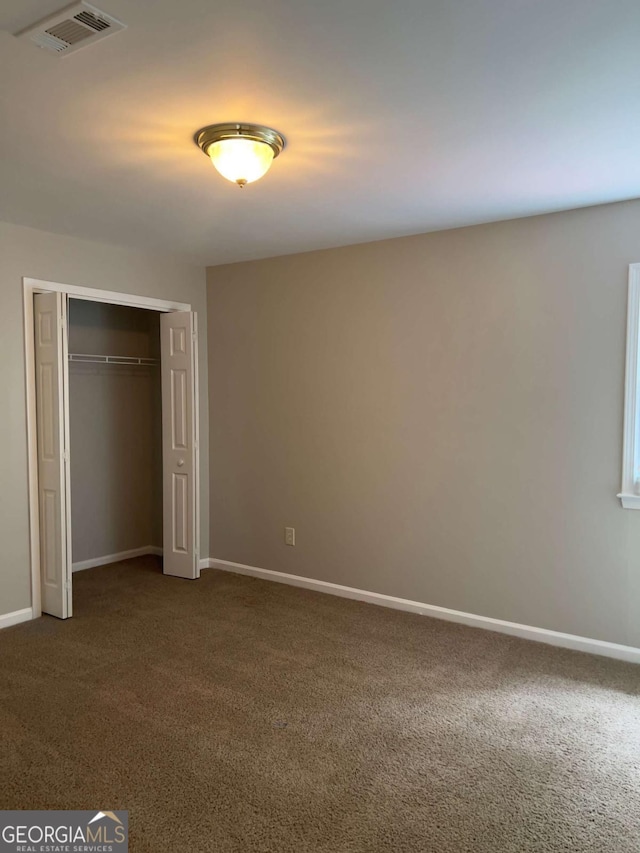unfurnished bedroom featuring dark colored carpet, baseboards, and a closet