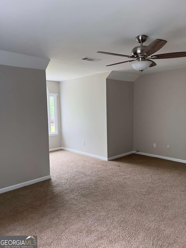 carpeted empty room with ceiling fan and baseboards