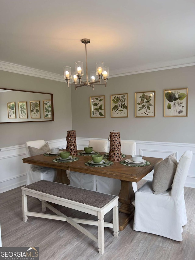 dining room featuring ornamental molding, a chandelier, wood finished floors, and a wainscoted wall