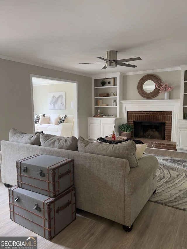 living room featuring a fireplace, wood finished floors, ceiling fan, and ornamental molding
