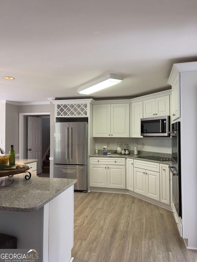 kitchen with black appliances, light stone counters, light wood-style floors, and white cabinetry