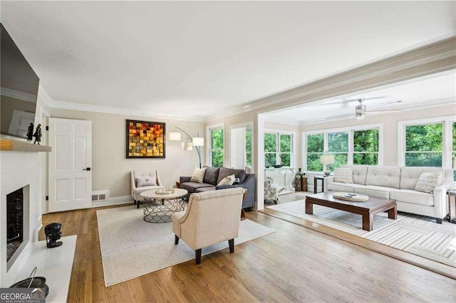 living area with crown molding, wood finished floors, a fireplace, and baseboards