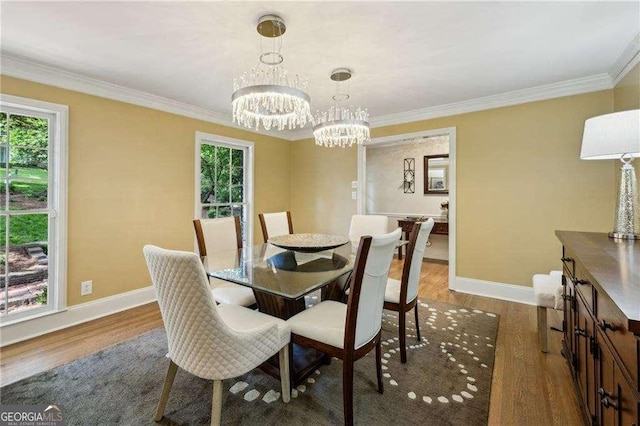 dining area featuring baseboards, wood finished floors, plenty of natural light, a chandelier, and ornamental molding