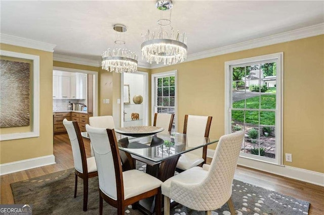 dining room featuring a chandelier, healthy amount of natural light, baseboards, and ornamental molding