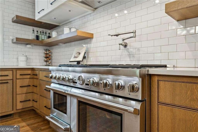 kitchen featuring double oven range, decorative backsplash, and brown cabinetry