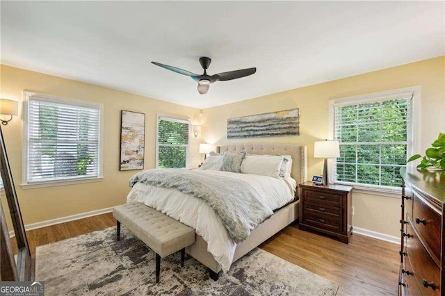 bedroom featuring baseboards, wood finished floors, and a ceiling fan