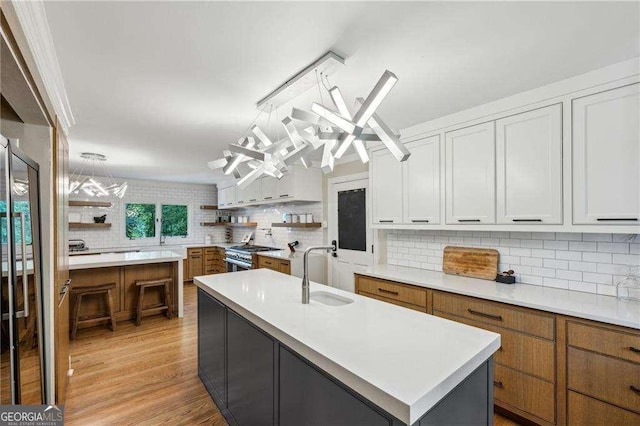 kitchen with a sink, open shelves, tasteful backsplash, and light countertops