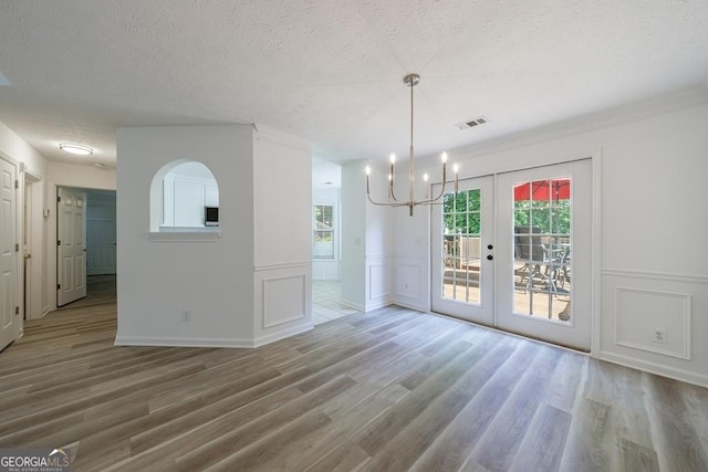 3350 Serenade Ct, Alpharetta, GA 30004 - unfurnished dining area with a decorative wall, a textured ceiling, wood finished floors, a chandelier, and french doors
