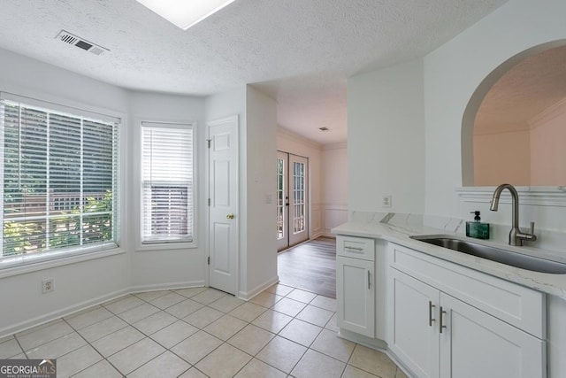 3350 Serenade Ct, Alpharetta, GA 30004 - kitchen featuring a sink, light tile patterned floors, white cabinetry, light stone countertops, and arched walkways