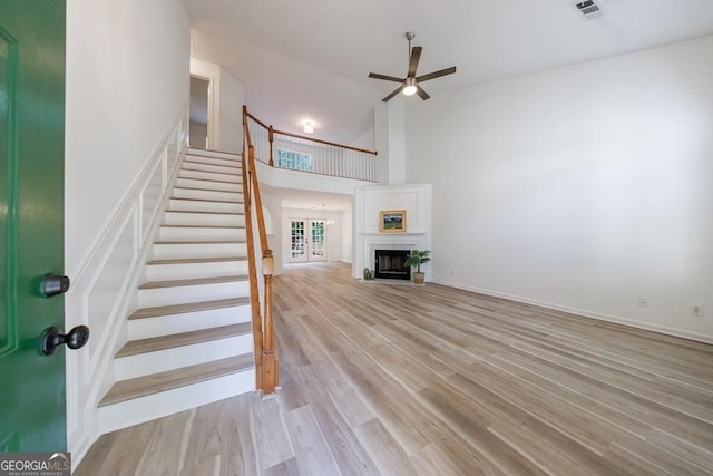 3350 Serenade Ct, Alpharetta, GA 30004 - unfurnished living room with stairs, a ceiling fan, wood finished floors, high vaulted ceiling, and a fireplace