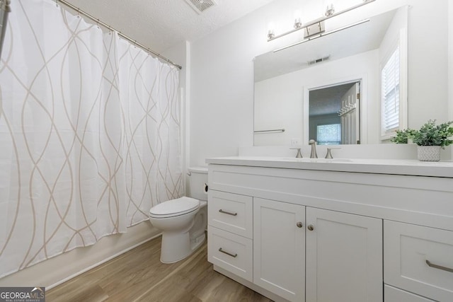 3350 Serenade Ct, Alpharetta, GA 30004 - bathroom featuring wood finished floors, toilet, vanity, a textured ceiling, and healthy amount of natural light