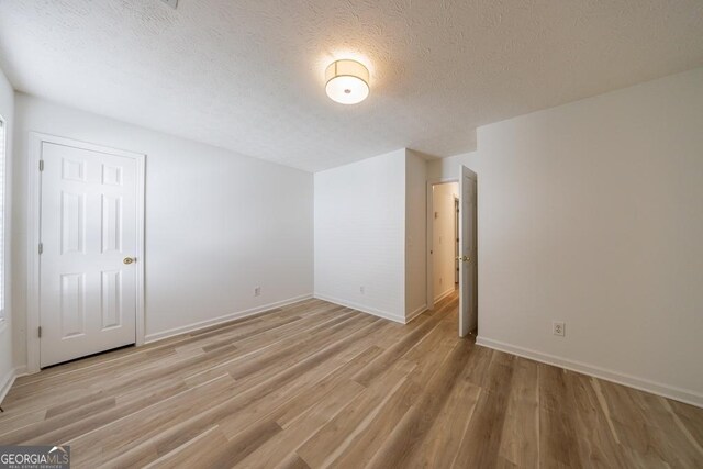 3350 Serenade Ct, Alpharetta, GA 30004 - unfurnished bedroom featuring light wood finished floors, a textured ceiling, and baseboards