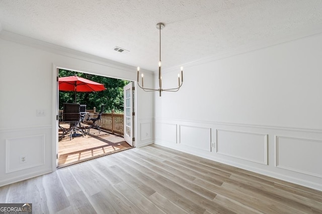 3350 Serenade Ct, Alpharetta, GA 30004 - unfurnished dining area with a decorative wall, a chandelier, light wood finished floors, a wainscoted wall, and a textured ceiling