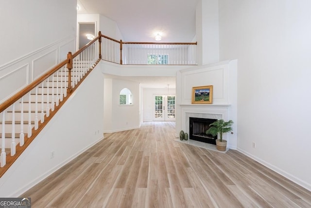 3350 Serenade Ct, Alpharetta, GA 30004 - unfurnished living room featuring stairs, wood finished floors, a fireplace with flush hearth, and a towering ceiling