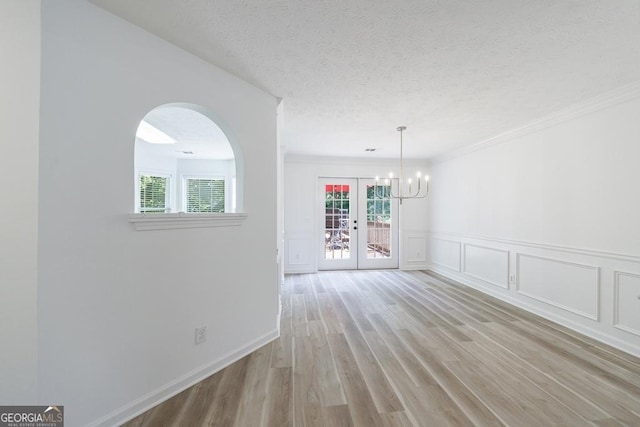 3350 Serenade Ct, Alpharetta, GA 30004 - empty room featuring healthy amount of natural light, a chandelier, light wood finished floors, crown molding, and a decorative wall