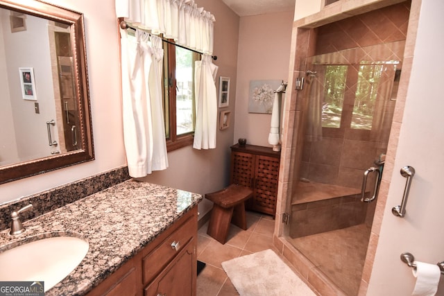 bathroom featuring healthy amount of natural light, a shower stall, vanity, and tile patterned floors