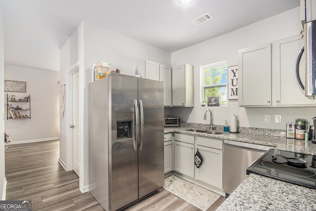 278 Lambert Overlook Cir, Carrollton, GA 30117 - kitchen featuring appliances with stainless steel finishes, a sink, light stone counters, light wood-style floors, and baseboards