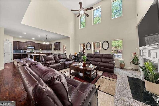 living room featuring a ceiling fan, baseboards, plenty of natural light, a towering ceiling, and recessed lighting