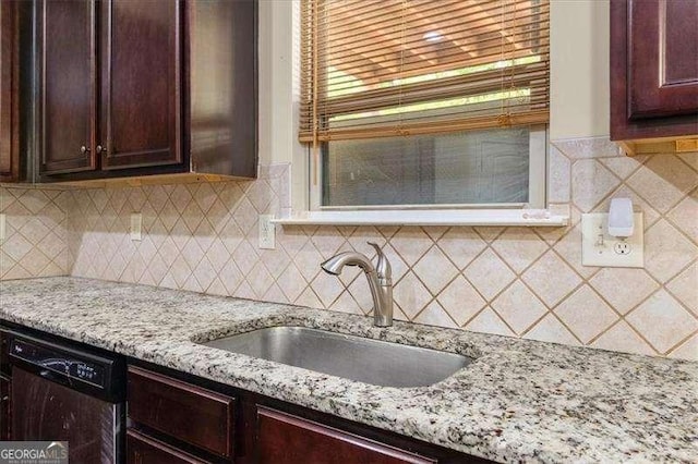 kitchen featuring dishwasher, a sink, light stone counters, and decorative backsplash