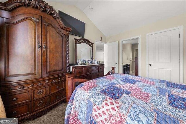 carpeted bedroom featuring vaulted ceiling and ensuite bathroom