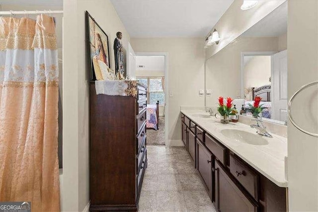 full bathroom featuring double vanity, baseboards, and ensuite bath