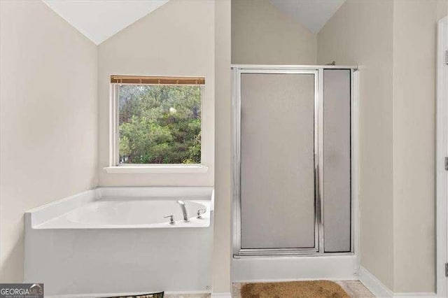 full bath with vaulted ceiling, a stall shower, and a garden tub